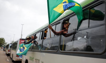 People hold Brazilian flags from the windows of a bus as they are taken to the federal police after a camp set by supporters of Brazil’s former president Jair Bolsonaro was broken up in Brasíliaon Monday.