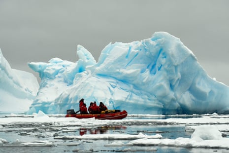 Australian Antarctic Division expeditioners cruise past icebergs in an inflatable boat near Mawson Station, Antarctica