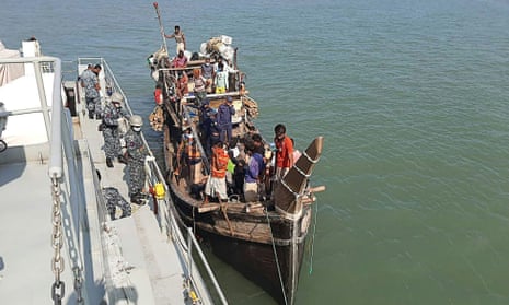 A Bangladeshi navy vessel takes a boat carrying Rohingya refugees alongside