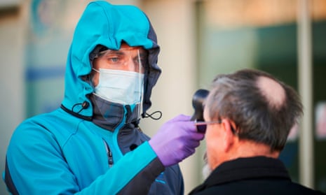A medical worker measures body temperature at one of the entrances of the Community Health Centre in Kranj, Slovenia on March 23, 2020.