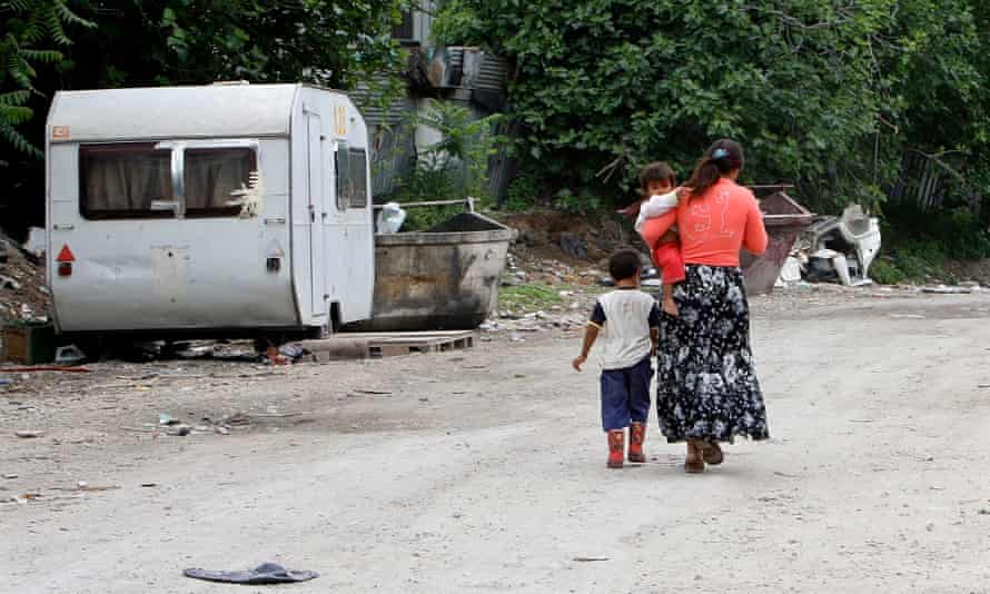 A Roma woman walks with her children in a camp in Rome.
