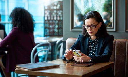 A woman sitting alone in a restaurant, looking at her phone