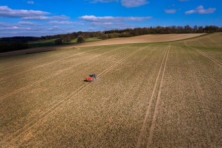 Um trator espalhando fertilizante em um campo enorme sem sebes visto de cima