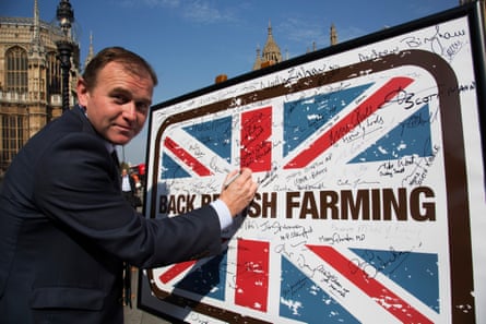 A man in a suit in front of a panel that features a union jack and the words ‘Back British Farming’.