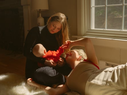 Leah sitting cross-legged adjacent a model holding their babe daughter, pinch Rosa lying connected nan level adjacent to them pinch her caput connected Leah’s knee, holding Mara’s hand