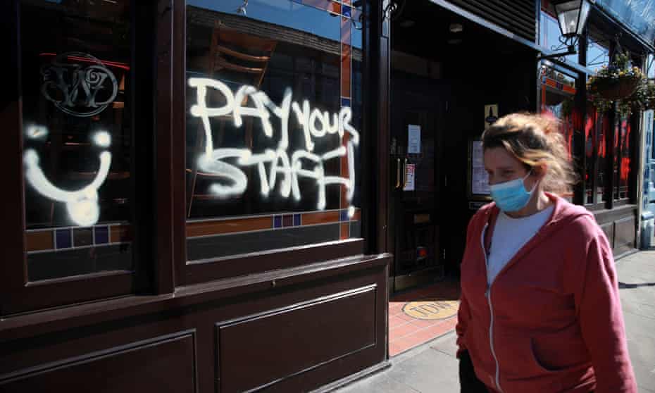 A person walks by graffiti that reads 'Pay your staff' on a JD Wetherspoon pub in Crystal Palace, south London