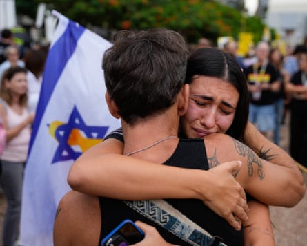 A man and a woman embrace with Israeli flag in background