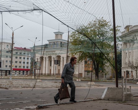 A woman walks beneath anti-drone nets in Oleshky.