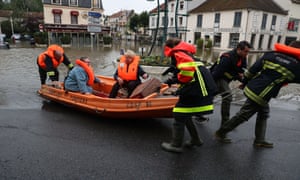 Firefighters evacuate people in a small boat from a flooded street after the Yvette river burst its banks.