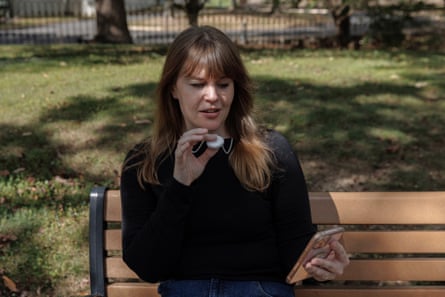 Madeleine Aggeler speaks into her Friend AI device on a park bench.