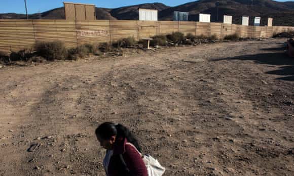 A woman walks past prototypes of Donald Trump's US-Mexico border wall.