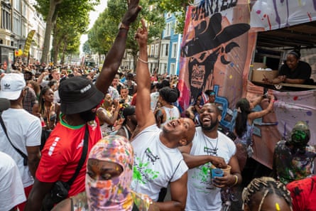 a crowd, mostly young men in the foreground, look happy and boisterous; they are raising their hands in the air and laughing