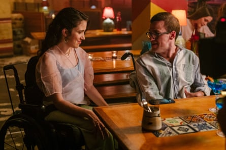 A still from Latecomers, a new SBS show premiering December 2022 in Australia, showing a man and a woman, both using wheelchairs, sitting at a table talking.