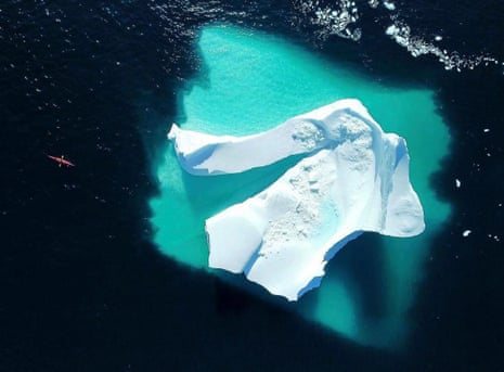 Aerial shot of Mike Keen kayaking past an iceberg