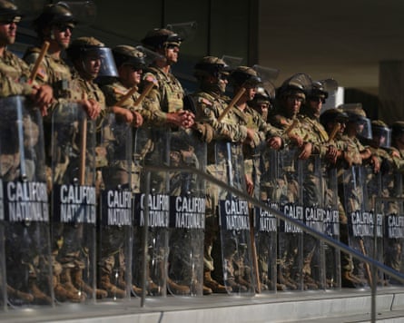 National guard in fatigues and riot gear hold batons and shields