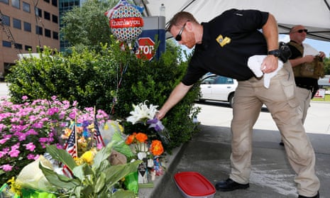 A Louisiana law enforcement officer places flowers on a makeshift memorial at Our Lady of the Lake regional medical center in Baton Rouge, Louisiana, on Monday.