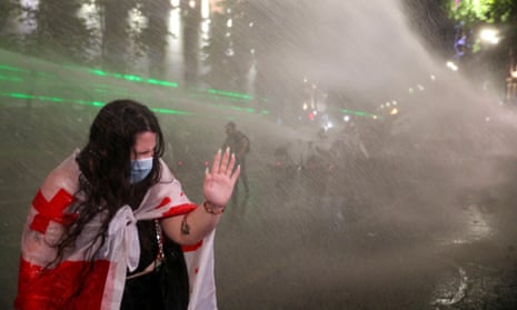 A woman reacts as law enforcement officers use a water cannon to disperse the crowd near the parliament building, during a rally to protest against a bill on ‘foreign agents’ in Tbilisi.