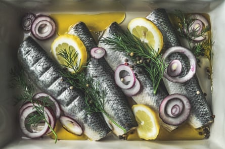 A dish of whole herring with lemon, red onion, dill and oil