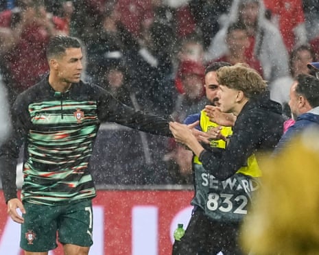 Cristiano Ronaldo greets a fan who was grabbed by stewards as he ran on to the pitch.