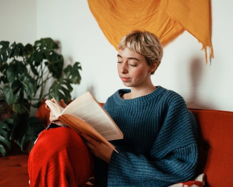 a young woman reading a book on a couch