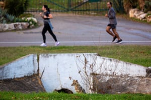 People jog near a jackal in Hayarkon Park in Tel Aviv, Israel, on 10 April. The timid animals have come into the open, reaching areas they rarely venture to as they search for food.