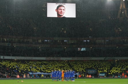 The Cardiff players gather for a period of silence in tribute to missing striker Emiliano Sala as the Cardiff fans hold up their yellow placards and the wreaths lie in the centre circle.