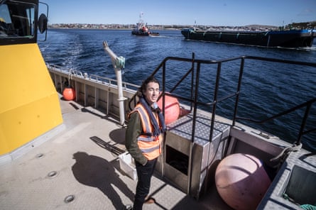James Wallace, squid fishing boss, stands on his launch’s deck with a tugboat behind him