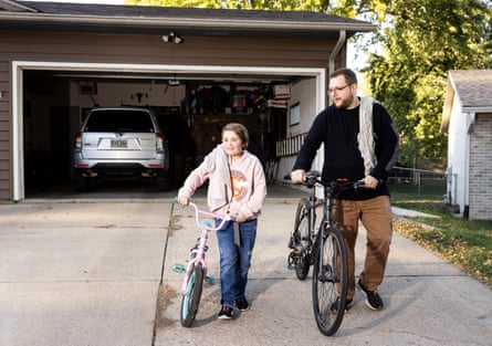 Alec Vanhove and his daughter, Norah, standing with their bikes outside their garage with their blankets on their shoulders