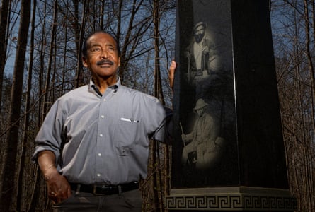 a man standing next to an outdoor monument surrounded by trees
