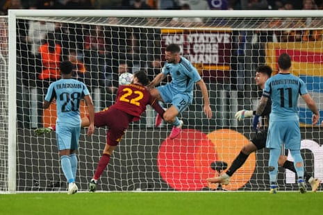 Roma's Mario Hermoso heads the ball into the net next to a jumping Slovan Bratislava player.