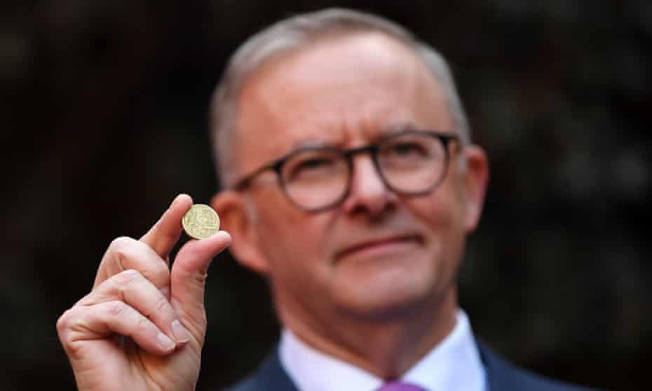 Australian Opposition Leader Anthony Albanese holds a one dollar coin as he speaks to the media