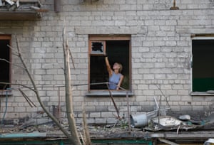 A woman removes broken glass in a damaged apartment building after shelling, which local Russian-installed authorities called a Ukrainian military strike, in Donetsk