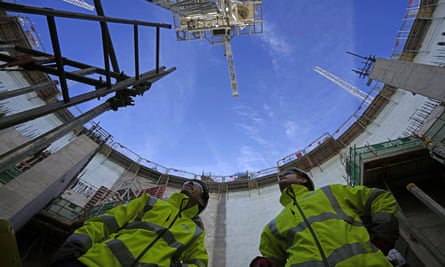 Workers looking up at the sky past curved walls under construction