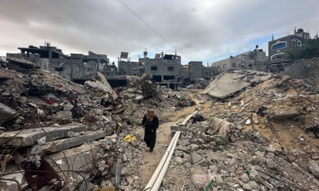 A Palestinian woman walks among the rubble of houses destroyed by Israeli airstrikes in Khan Younis.