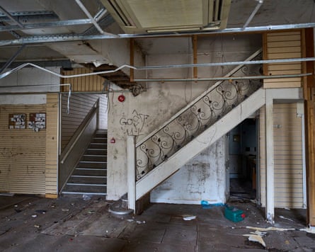 An ornate staircase at the back of a rundown room