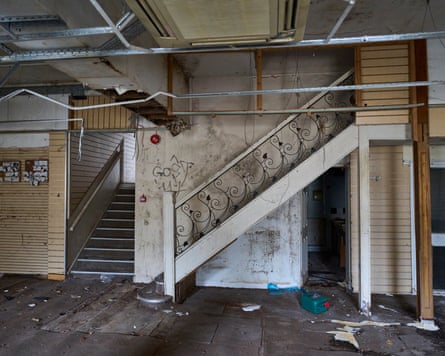 The derelict interior of a former department store, showing an ornate staircase in disrepair