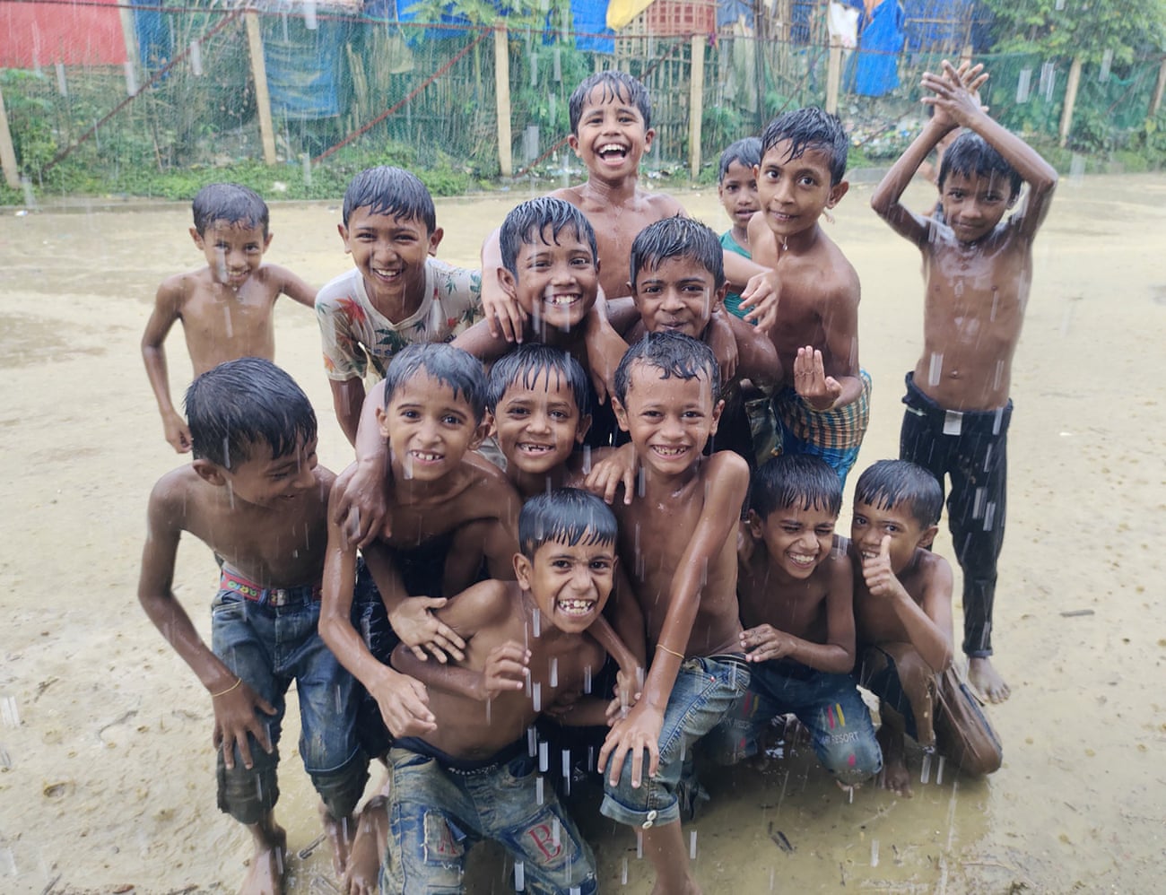 En gruppe rohingyabarn leker i regnet mens det strømmer ned utenfor tilfluktsrommene deres i flyktningleirene i Cox's Bazar, Bangladesh.