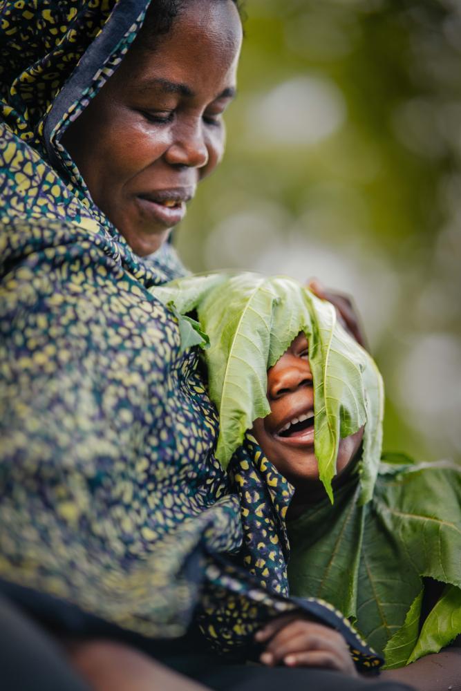 mother, child and leaves over the child’s face
