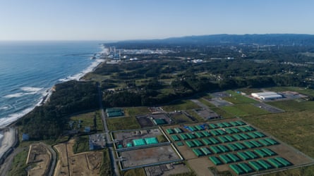 Aerial view of a nuclear waste storage area in Futaba, with the Fukushima Daiichi nuclear power plant in the background.