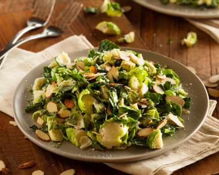 A photograph of a plate of kale and brussel sprout salad with almonds, on top of a white napkin.
