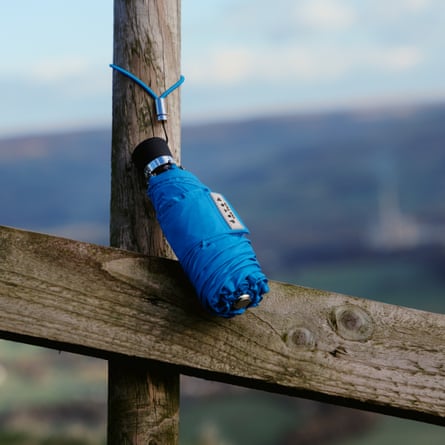 Folded-up compact umbrella with its string handle hooked on to fence post