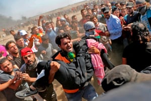 Palestinians carry a wounded demonstrator away from the protest zone, one of hundreds needing care from an already stretched medical system in Gaza