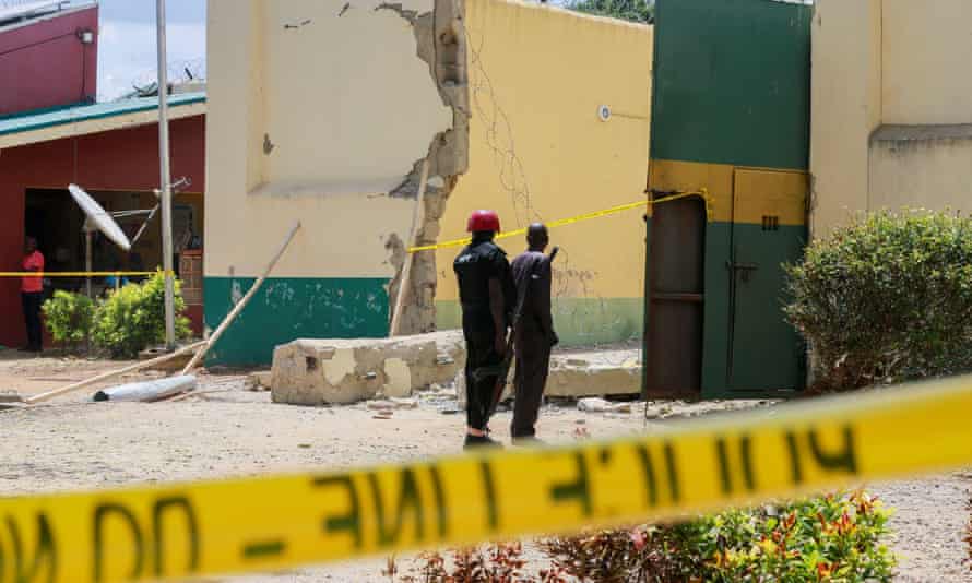 Prison officials stand near a gate destroyed during the prison break in Kuje, near the capital, Abuja