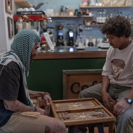 Two people sit playing a board game with cafe counter behind