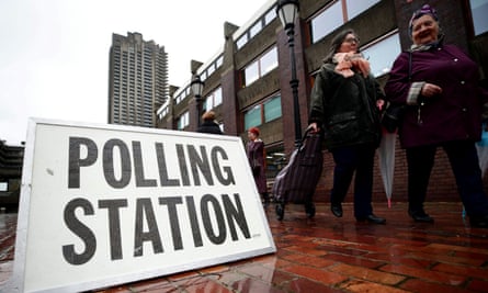 people walk past a polling station sign in london