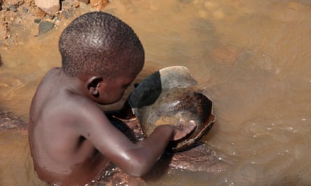 Five-year-old Desire Matanda uses a pan to search for particles of gold along the Odzi River in Mutare. Poverty has forced many children in Zimbabwe out of school and into work.
