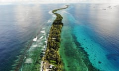 An aerial view of a narrow strip of land in Funafuti, Tuvalu, with blue waters on each side.