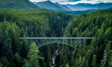 A bridge is surrounded by trees and mountains.
