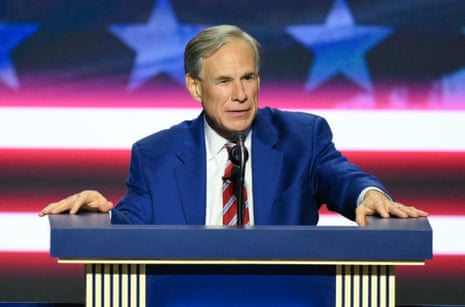 greg abbott, a man in a blue suit, speaks at a podium with his hands spread, in front of a starred backdrop