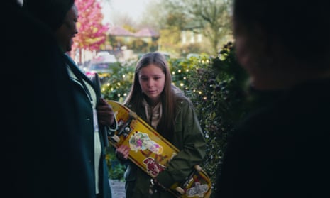 A downcast teenage girl carries a skateboard as she waits to be let in the house in the John Lewis Christmas advert 2022